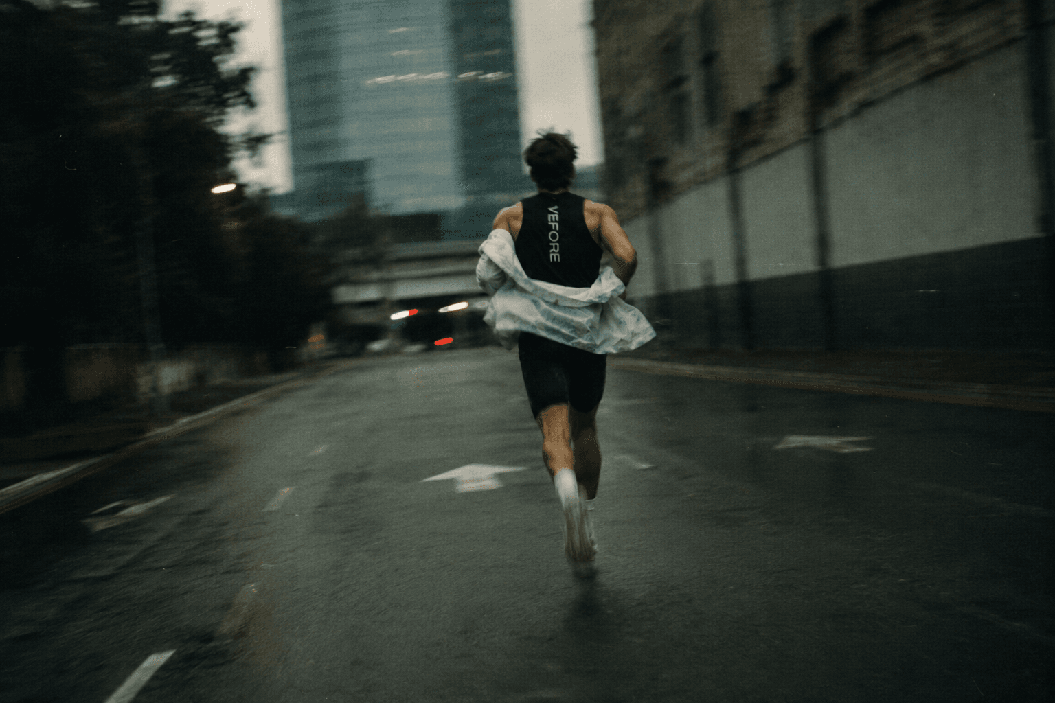 A VEFORE runner, mid-stride on a city street at dusk
